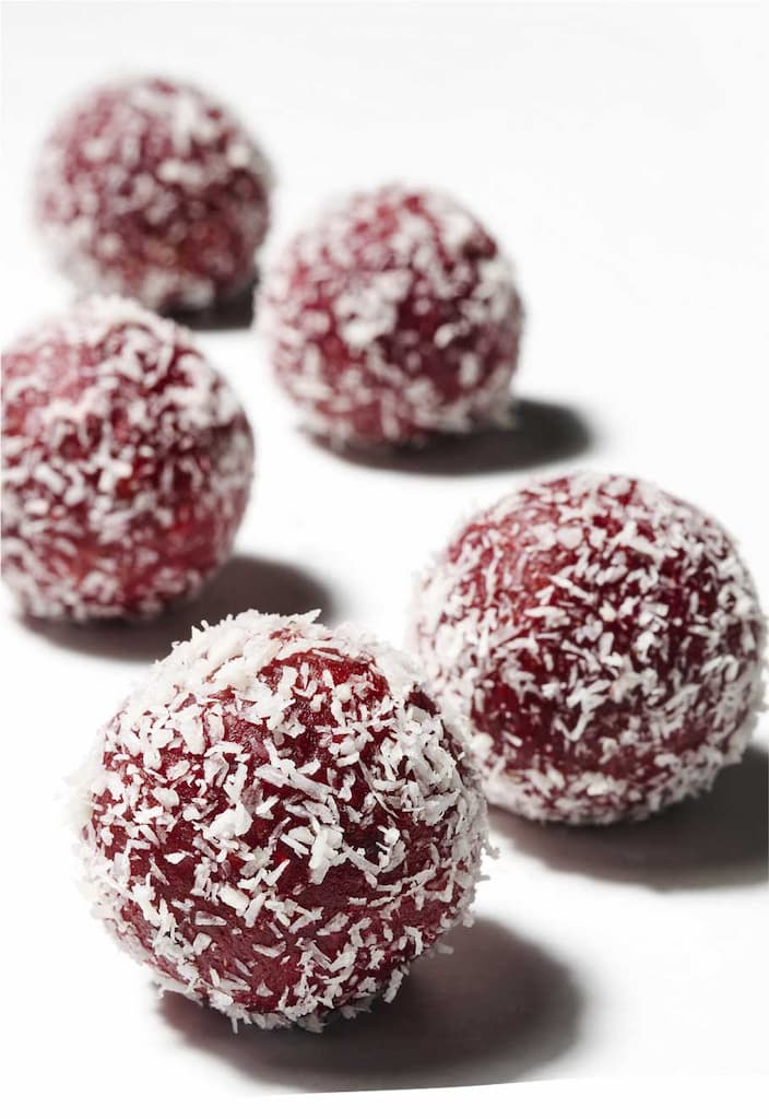 vegan raw balls with coconut shavings on white.